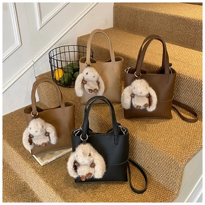 Detail of minimalist bucket bags in four colors with cute bunny charms and leather texture
