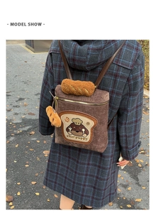 Detail of a brown corduroy backpack featuring Chef puppy embroidery and bread plush charms