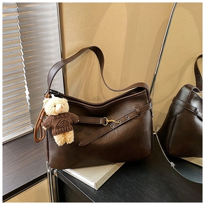 Vue détaillée du sac cabas en cuir marron foncé avec boucle élégante et accessoire petit ours