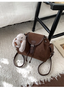 Close-up of retro brown suede backpack with drawstring and plush rabbit pendant