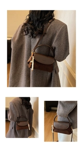 Detail of dark brown suede crossbody bag with leather strap and bohemian beaded charm accessory