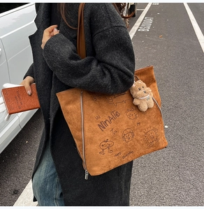 Détail du sac fourre-tout marron en suédine avec imprimé et pendentif ours en peluche