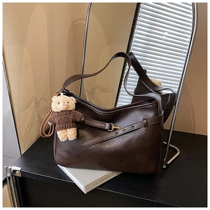 Détail du sac à bandoulière marron foncé en similicuir avec boucles et pendentif ours peluche