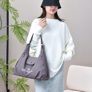 Detail of grey nylon tote bag showing front flap closure and white brand lettering