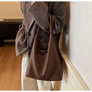 Detailed weave pattern on a large dark brown tote bag worn over the shoulder
