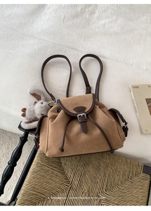 Detail view of retro brown suede backpack with leather trim and drawstring closure on chair