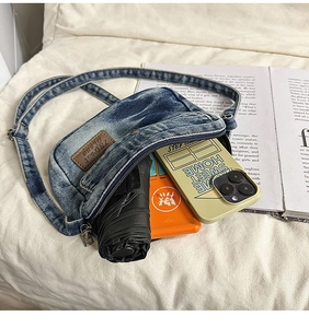 Detail showing the denim crossbody bag storage space for phone, umbrella, and essentials