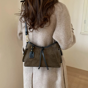 Detail view of the olive suede crossbody bag with leather trim on a beige wool coat