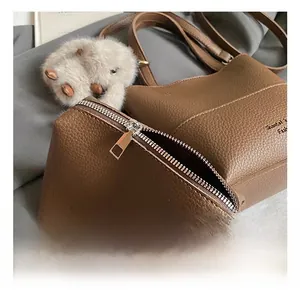 Detail of brown litchi pattern leather bucket bag set with plush charm and silver hardware