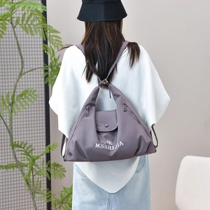 Rear view of model wearing a purple-grey nylon multi-functional backpack tote with logo