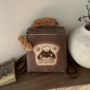 Detail of chef puppy embroidery and bread plush handle on brown corduroy backpack