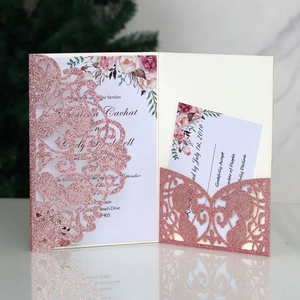 Detail of laser-cut wedding invitation with pink glitter and floral inner card