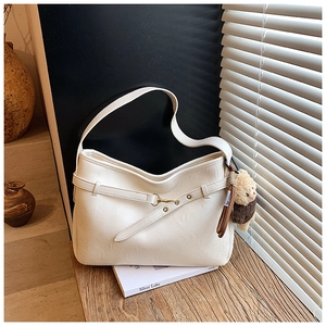 Détail d'un sac porté épaule crème avec texture cuir et pendentif ours brun mignon