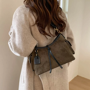 Detail of tan suede shoulder bag with black leather trim and decorative tie knot detail