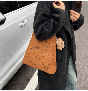 Détail du sac cabas en daim marron avec imprimé chat mignon et pendentif ours en peluche