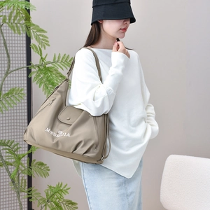 Detail of khaki tote bag with MSSEBIA embroidery shown on a model in a natural setting