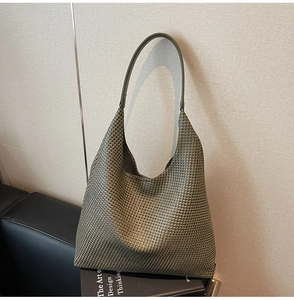 Close-up of olive green woven tote bag with intricate texture and leather straps