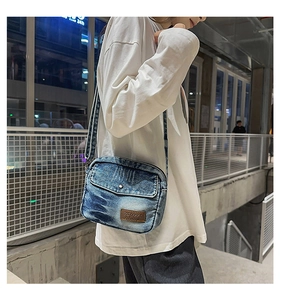 Outdoor side view of washed blue denim crossbody bag with adjustable wide strap