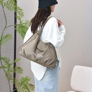 Detail view of khaki nylon tote bag featuring a side zipper pocket and brand logo