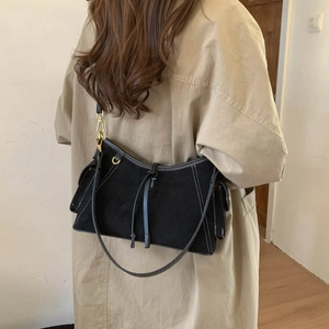 Detail of vintage black suede crossbody bag with white stitching and gold hardware ring