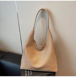 Close-up of woven tote bag with brown houndstooth texture and leather shoulder strap