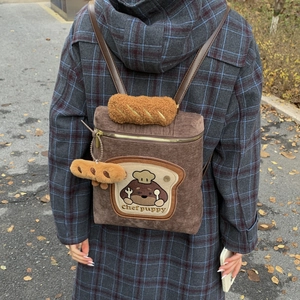 Detail of dark brown corduroy backpack with Chef Puppy embroidery and plush baguette decor