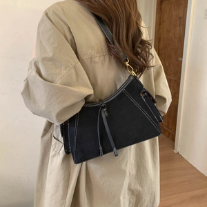Detailed view of black suede shoulder bag with contrast stitching and gold metal buckle