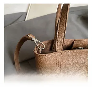 Close-up of silver metal hook and reinforced double stitching on brown lychee leather bag