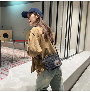 Détail du sac bandoulière en jean délavé avec patch en cuir brun et poche à rabat