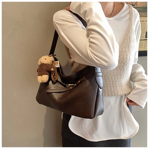 Détail du sac cabas en cuir marron foncé avec boucle décorative et pendentif ours peluche