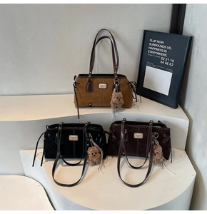 Detailed shot of suede tote bags in brown and black with plush bear charms on white steps