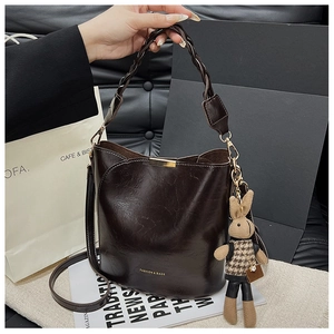 Detail of dark brown leather bucket bag with woven handle and plaid rabbit charm