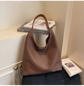 Close-up of brown woven texture and leather strap on a spacious retro hobo tote bag