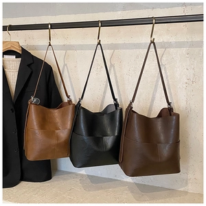 Dettaglio di grandi borse a secchiello in pelle in tre colori con tasche anteriori