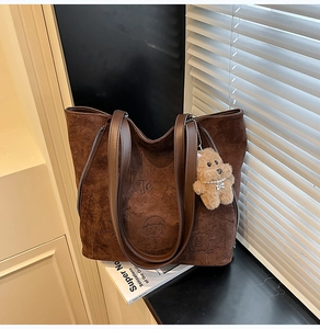 Détail du sac cabas en daim marron avec gaufrage dessin animé et breloque ours en peluche