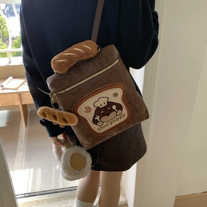 Detail view of corduroy backpack with chef puppy embroidery and baguette plush handle