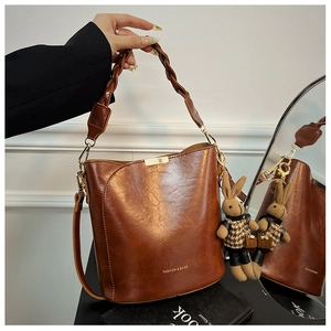 Brown oil wax bucket bag with woven handle and checkered bunny charm detail