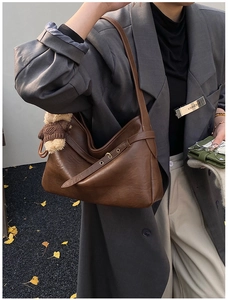 Détail du sac hobo marron vintage avec un pendentif ours mignon sur la bandoulière