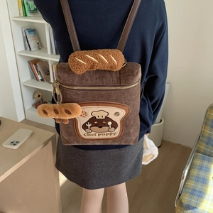 Close-up of brown corduroy backpack with embroidered chef puppy and plush baguette handle