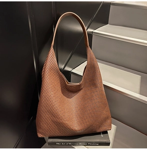 Detailed close-up of brown woven texture on a large hobo tote bag against stairs