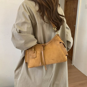 Detail of vintage suede shoulder bag in tan with leather tassels and side pocket