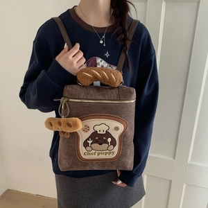 Detail of brown corduroy backpack featuring puppy embroidery and croissant plush handle