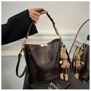 Detail view of dark brown bucket bag featuring woven handle and a cute rabbit charm