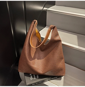 Detail of woven brown tote bag featuring yellow lining and smooth leather handle strap
