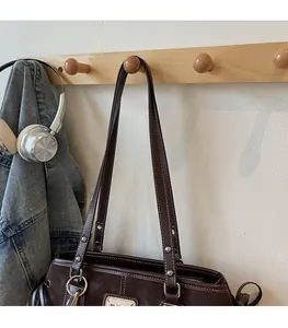 Detail of dark brown leather tote bag with contrast stitching and silver stud accents