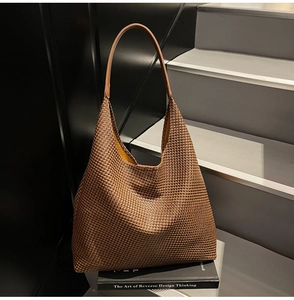 Detailed texture of brown woven hobo bag placed on books in a stylish urban setting