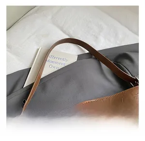 Dettaglio della tracolla regolabile e texture in pelle vintage della borsa a secchiello