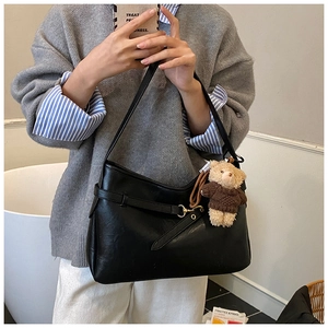 Détail du sac à épaule en cuir noir avec boucle dorée et pendentif ours marron mignon