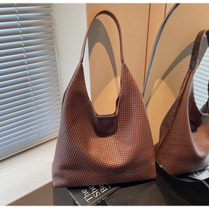 Detailed view of dark brown woven texture and smooth leather strap on large hobo bag