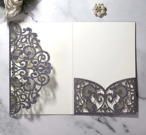 Detailed laser cut purple glitter wedding invitation sleeve on marble surface